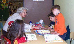 senior woman working with three kids at table